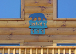 Welcome sign with house number on log cabin